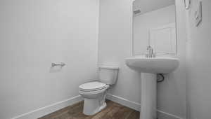 Half bath with toilet and wood finished floors