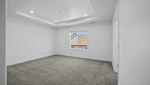Carpeted spare room with a tray ceiling and recessed lighting