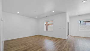 Empty room featuring wood finished floors, a textured ceiling, and recessed lighting