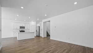 Unfurnished living room with recessed lighting, dark wood finished floors, and stairway