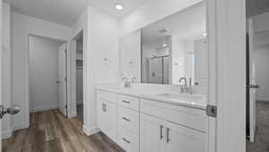 Full bath featuring a stall shower, double vanity, wood finished floors, and a walk in closet