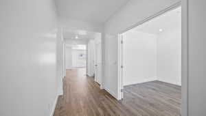 Hallway with wood finished floors and recessed lighting