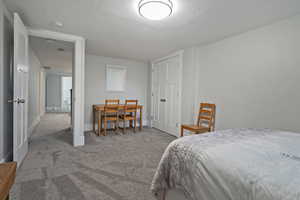 Carpeted bedroom featuring baseboards and a textured ceiling