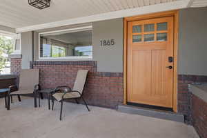 Doorway to property with brick siding and a porch