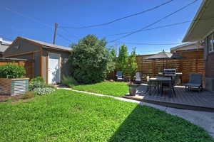 View of green lawn featuring a wooden deck and an outbuilding