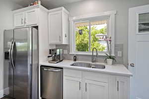 Kitchen with appliances with stainless steel finishes, decorative backsplash, light countertops, and white cabinets