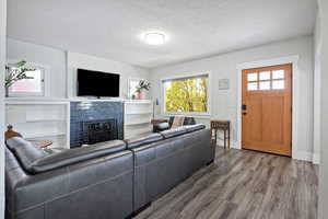 Living area featuring wood finished floors, a textured ceiling, and a fireplace