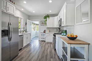 Kitchen featuring stainless steel appliances, dark wood finished floors, backsplash, white cabinets, and recessed lighting
