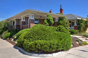 View of front of house featuring brick siding, covered porch, and a chimney