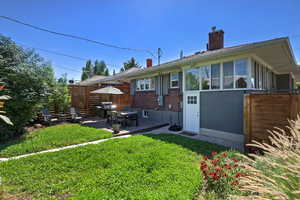 Back of house featuring a chimney, brick siding, and a patio