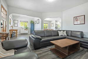 Living area featuring arched walkways, healthy amount of natural light, wood finished floors, and a textured ceiling