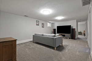 Living area with carpet and a textured ceiling