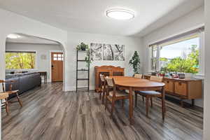Dining area with plenty of natural light, dark wood-style floors, and arched walkways