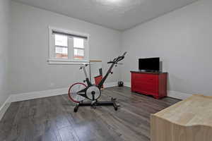 Exercise area with wood finished floors and a textured ceiling