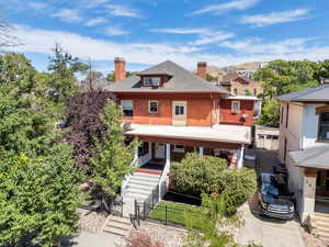 View of front of property featuring a chimney, a fenced front yard, covered porch, and stairway