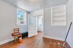 Unfurnished room with a textured ceiling, hardwood / wood-style floors, and built in shelves