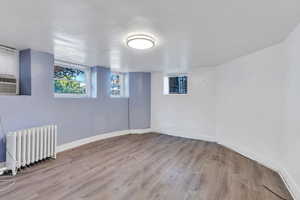 Below grade area with radiator and wood finished floors