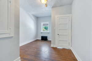 Corridor featuring a textured ceiling, radiator, and wood finished floors