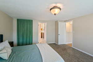 Carpeted bedroom featuring a textured ceiling and connected bathroom
