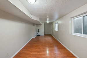 Below grade area featuring light wood-style floors and a textured ceiling