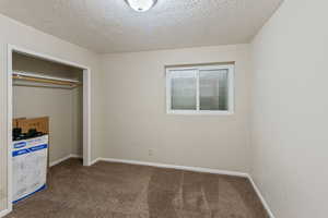 Unfurnished bedroom featuring carpet floors, a textured ceiling, and a closet