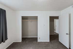 Unfurnished bedroom featuring carpet flooring, a textured ceiling, and a closet