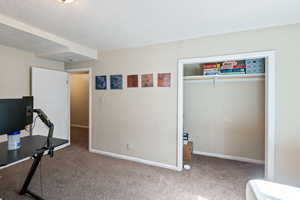 Carpeted office space with a textured ceiling