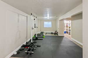 Workout room featuring baseboards and a textured ceiling