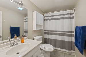 Bathroom featuring a textured ceiling, vanity, tile patterned floors, and a shower with curtain
