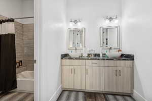 Bathroom with shower / bath combination with curtain, double vanity, and wood finished floors