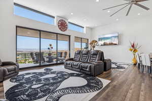 Living room with wood finished floors, a textured ceiling, recessed lighting, and a towering ceiling