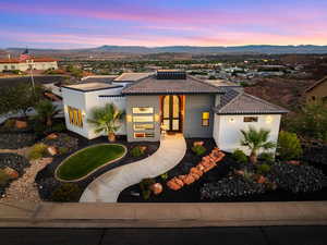 View of front of house with a tiled roof, stucco siding, a mountain view, and roof mounted solar panels
