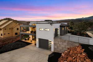 Contemporary home featuring a balcony, stucco siding, an attached garage, and driveway