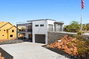 Contemporary house with a balcony, stucco siding, an attached garage, and concrete driveway