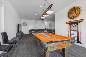 Recreation room featuring dark colored carpet, ceiling fan, and recessed lighting