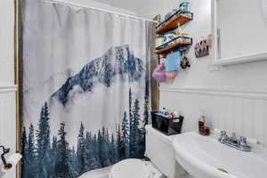 Full bathroom with a wainscoted wall, a decorative wall, and curtained shower
