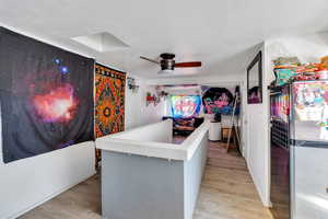 Bar with freestanding refrigerator, a textured ceiling, light wood finished floors, and ceiling fan