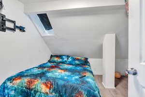 Bedroom featuring wood finished floors and vaulted ceiling