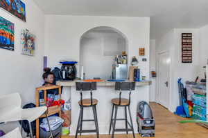 Kitchen featuring light wood-type flooring, a kitchen bar, arched walkways, and freestanding refrigerator