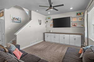 Carpeted living room with stairway and a ceiling fan