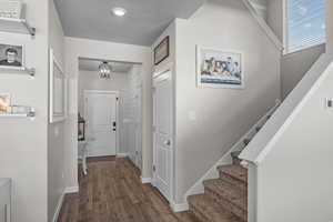 Foyer entrance with stairway, dark wood-style floors, and a textured ceiling