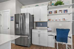 Kitchen with stainless steel fridge with ice dispenser, open shelves, light countertops, white cabinetry, and tasteful backsplash