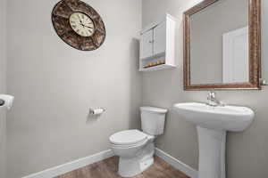 Half bath featuring baseboards and wood finished floors