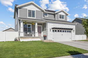 Craftsman-style house featuring covered porch, a garage, driveway, and stone siding