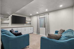 Living room with a textured ceiling, light colored carpet, and recessed lighting