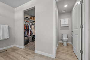 Bathroom with wood finished floors and a walk in closet