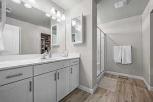 Full bath with wood finished floors, vanity, a stall shower, a textured ceiling, and a walk in closet