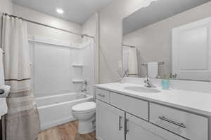 Full bathroom with vanity, shower / bath combo with shower curtain, and wood finished floors