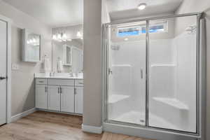 Bathroom with a stall shower, vanity, wood finished floors, and a textured ceiling