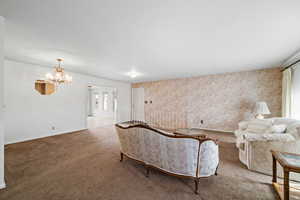 Living room featuring carpet flooring, wallpapered walls, and a chandelier